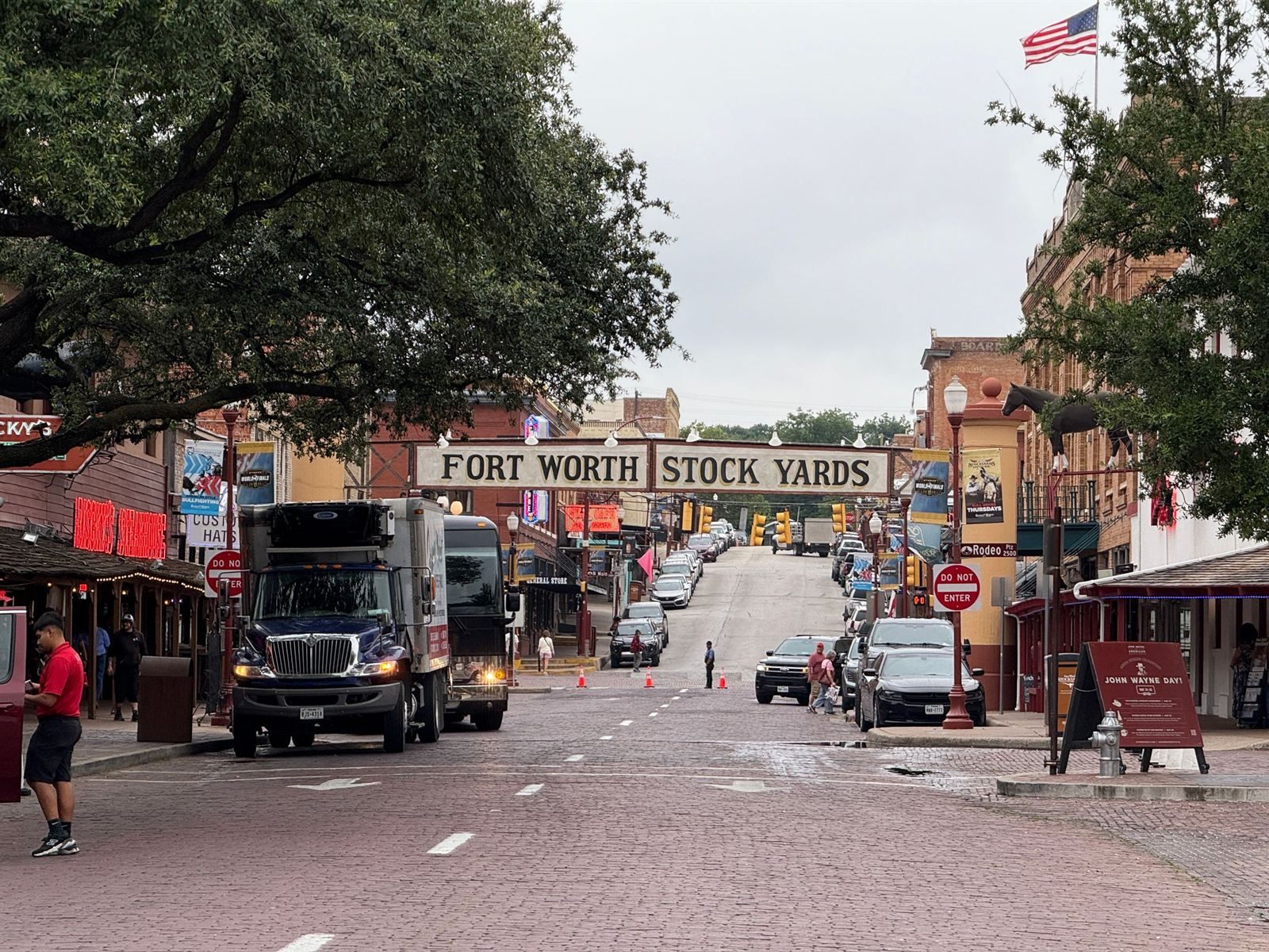 The Fort Worth Stock Yards sign over brick-paved Exchange Avenue, with western storefronts and an American flag